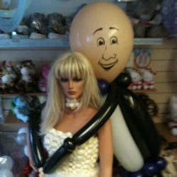A mannequin wearing a wedding dress made from white balloons, with a balloon groom