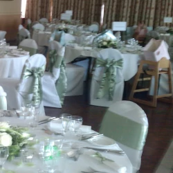 White chair covers with sage green sashes, around a round table