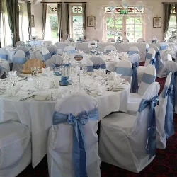 Wedding reception with white chair covers and perrywinkle blue sashes